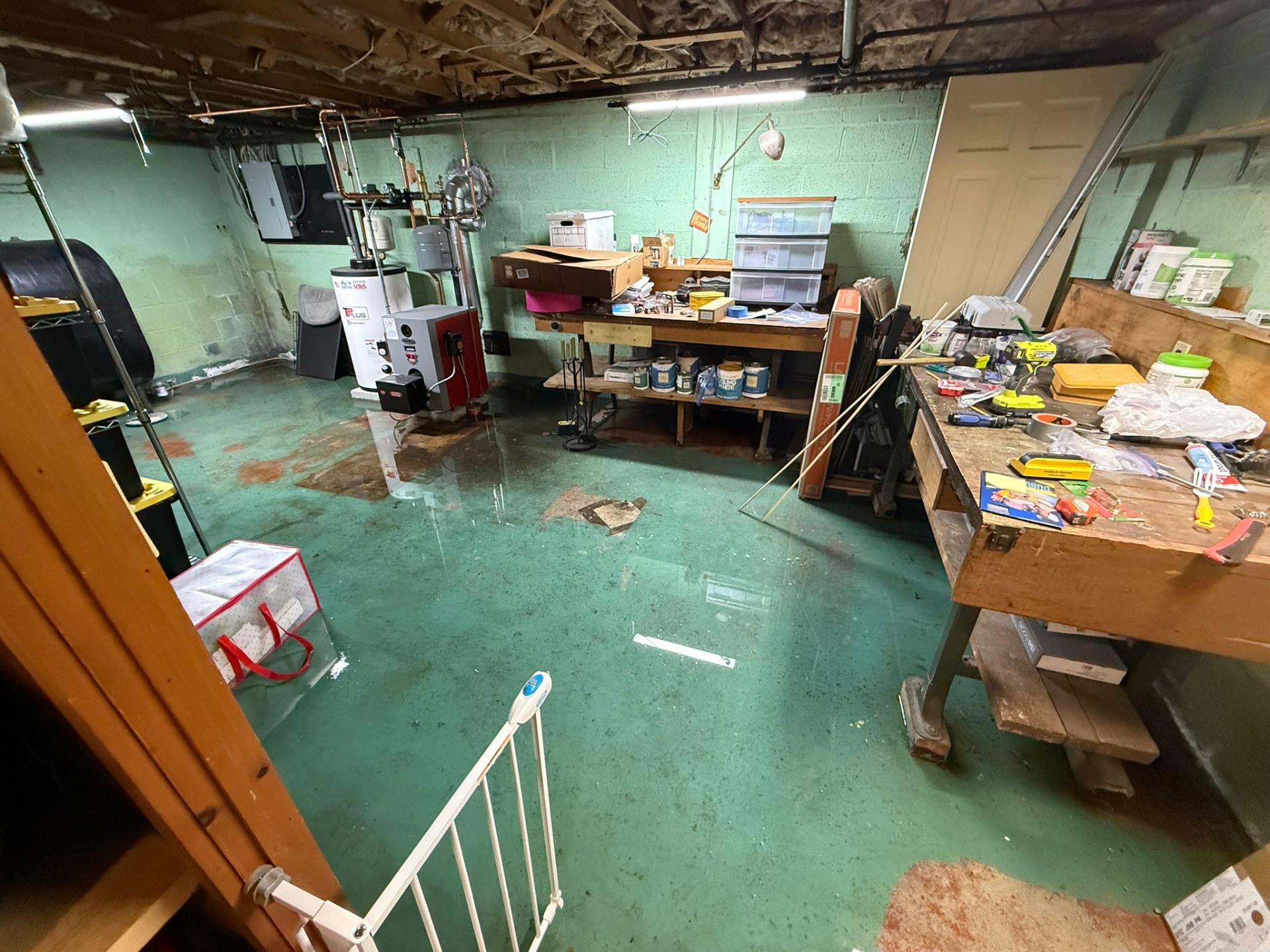 Standing water across a Connecticut basement floor after a failure near the boiler and water heater — first priority is extraction and killing the moisture source.