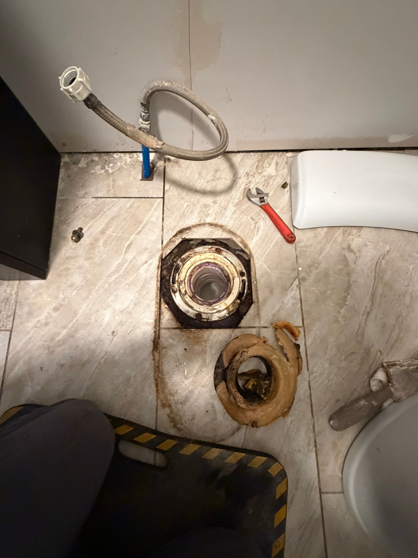 Drain Wizard toilet replacement job showing the removed toilet, exposed flange, old wax ring and work area