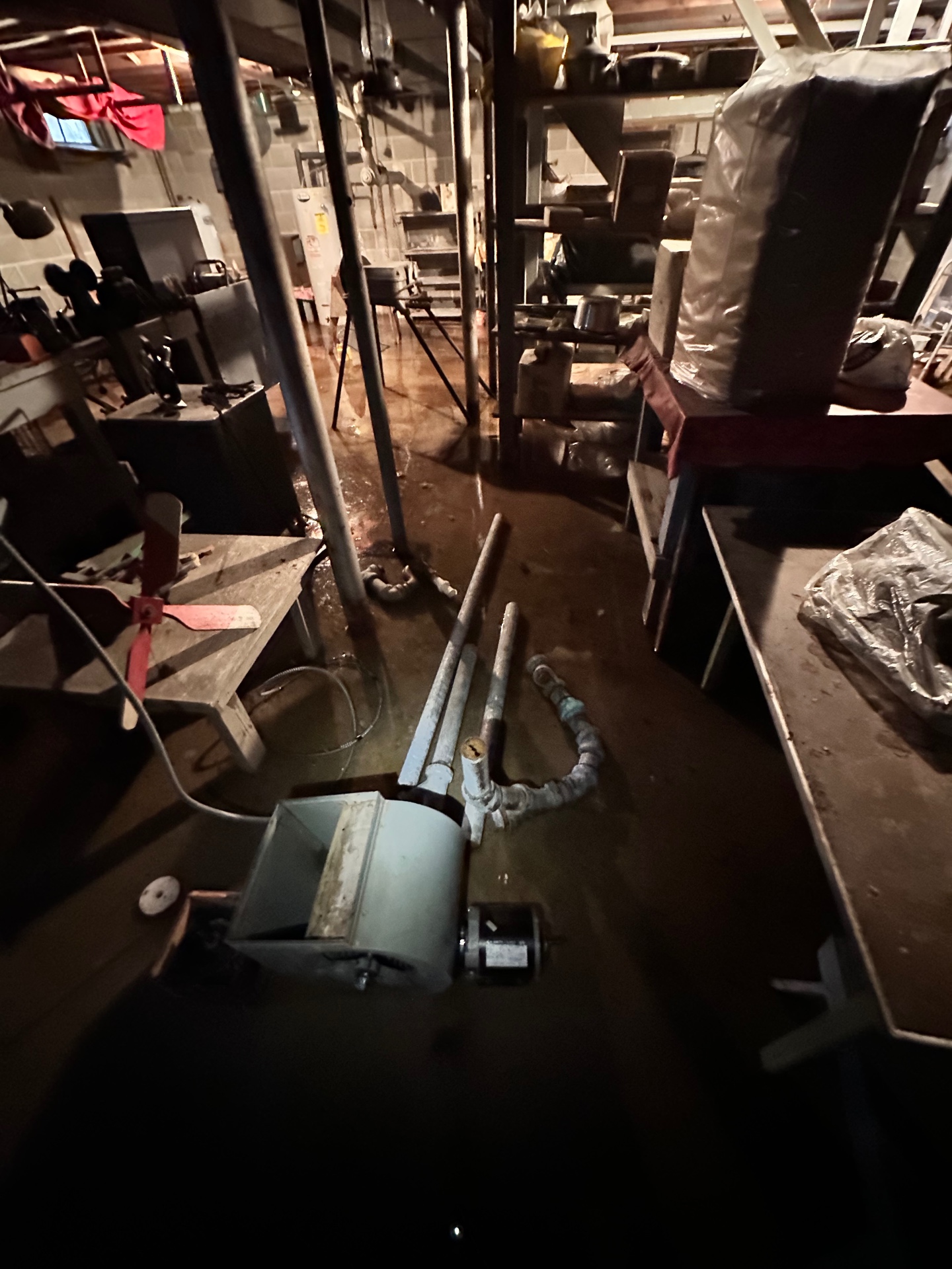 Flooded Madison, CT basement with standing water around an older boiler and workbenches