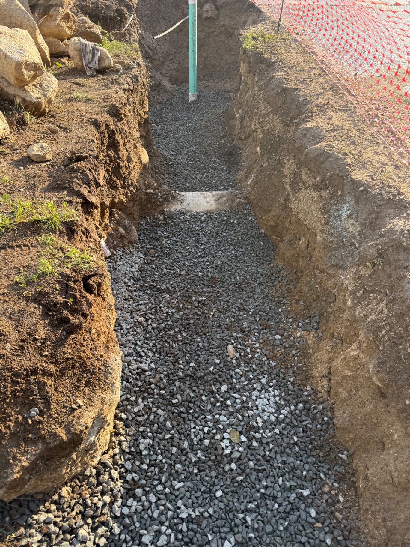 Bedding detail: a full envelope of 3/4" crushed stone under, around, and over the pipe. This is the difference between a repair that lasts 5 years and one that lasts 50.