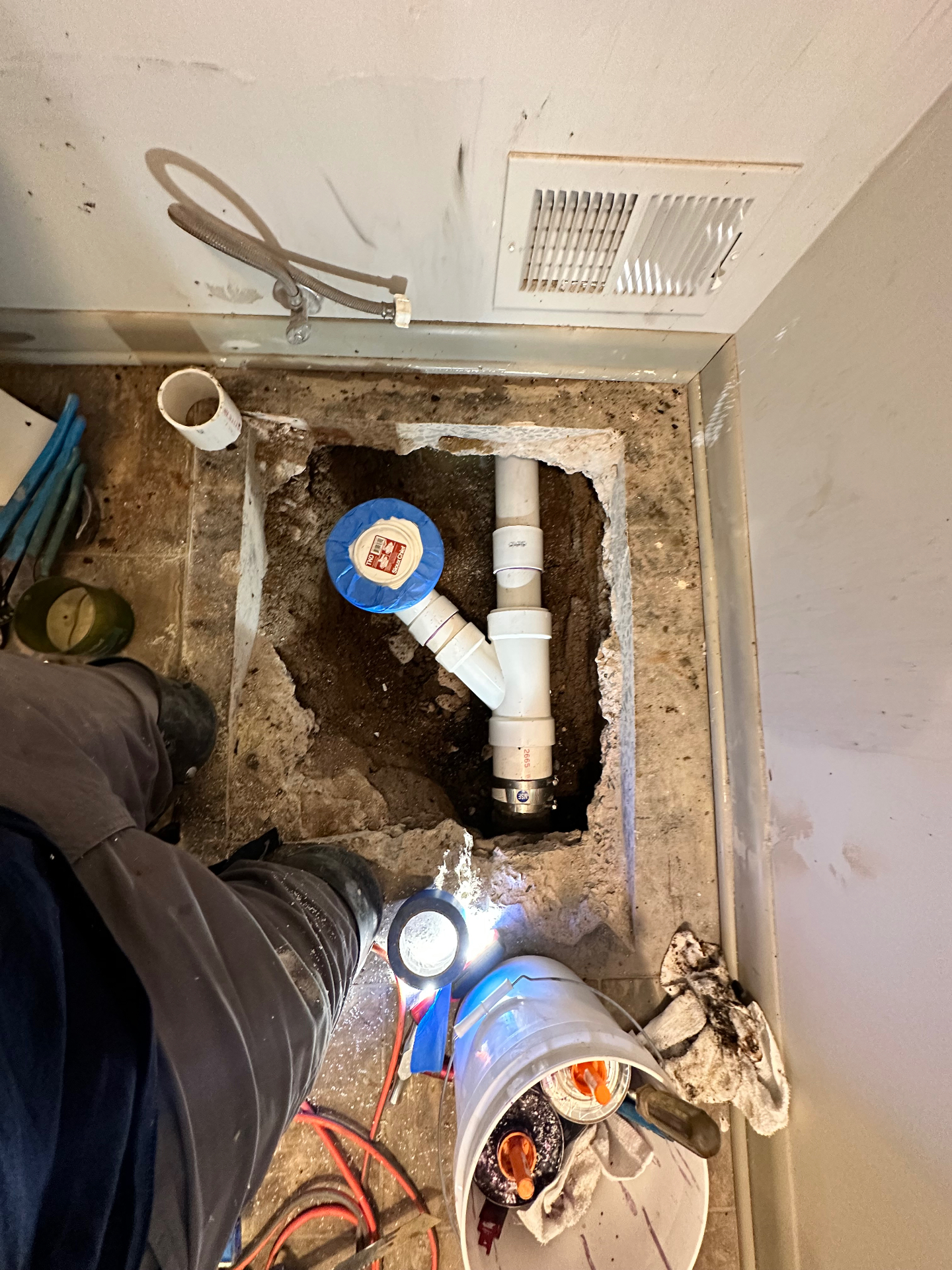 New PVC drain rough-in with cleanout set in an opened floor of a Madison bathroom