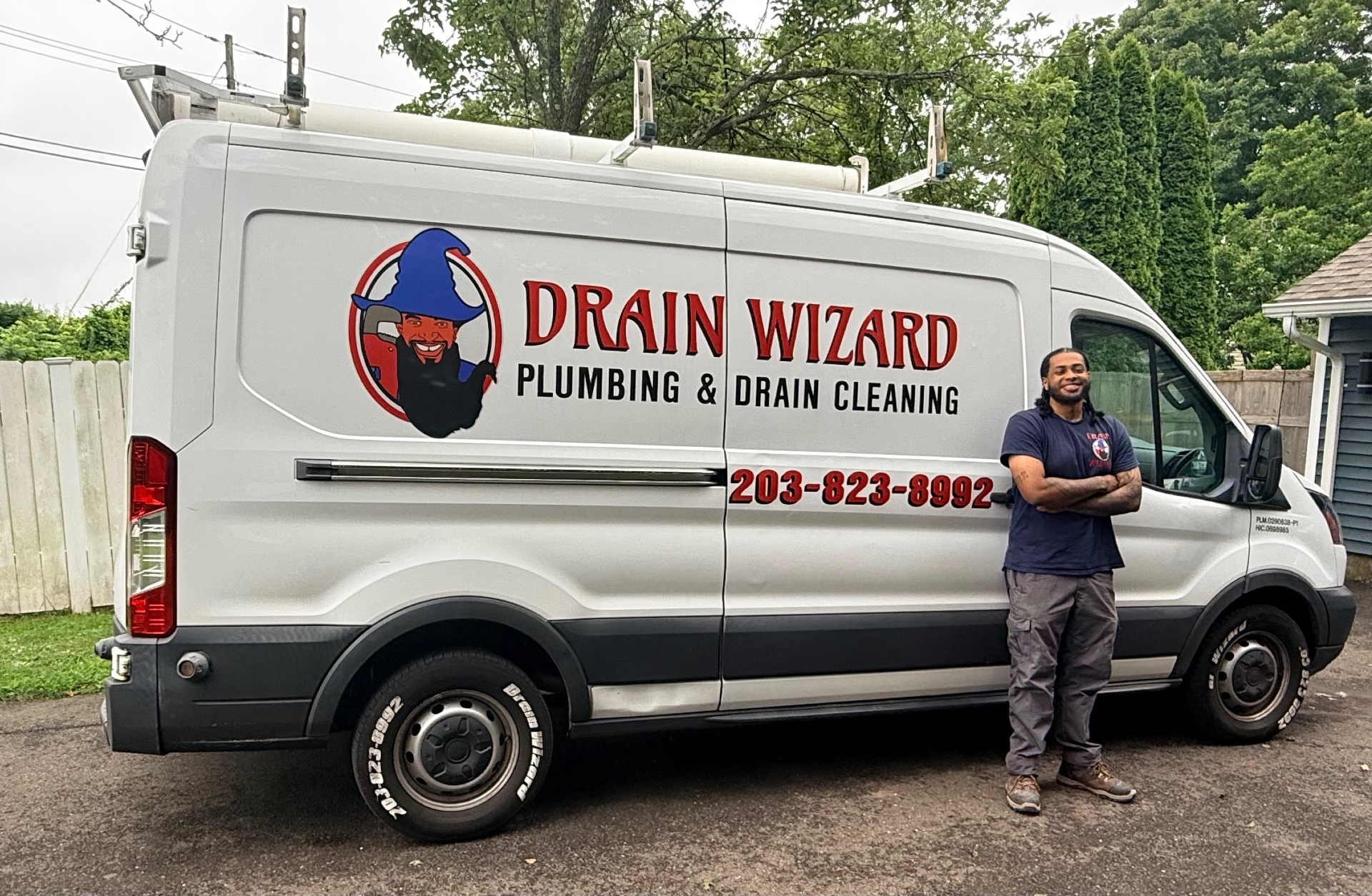 Corey Wallace, Plumbing Technician at Drain Wizard Plumbing, standing next to the branded service van