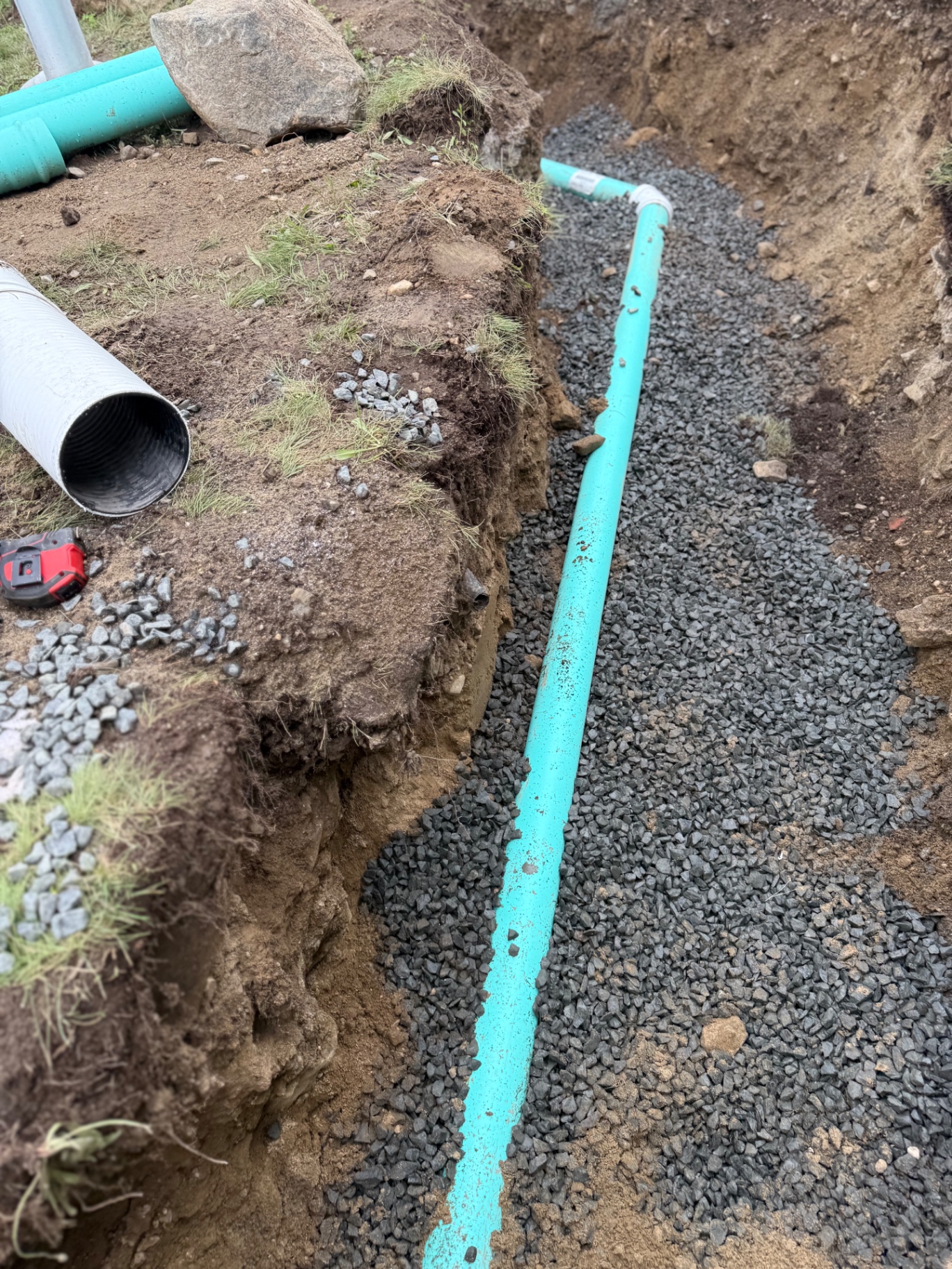 New branch line tied in and bedded in 3/4" crushed stone — clean, straight run at proper slope, ready for cover.