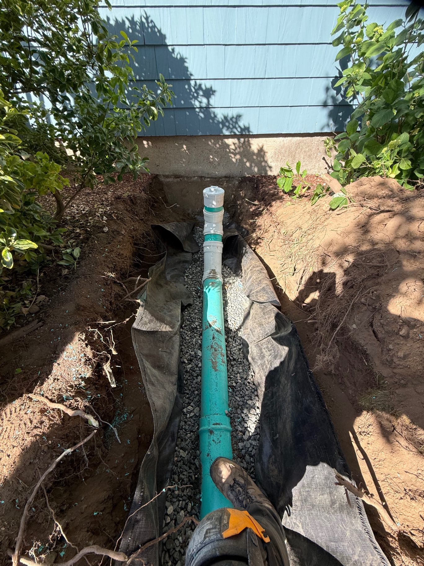 Side-yard sewer replacement in a tight residential run — new PVC laid on stone with filter fabric to keep silt from migrating into the bedding over time.