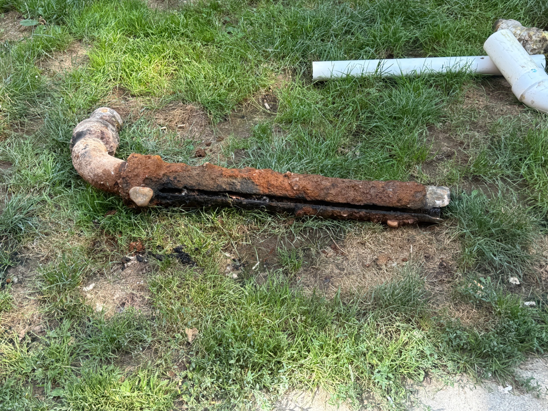 The culprit: original cast iron drain pipe suffering from trench rot — the bottom of the pipe fully eroded away from decades of waste flow.