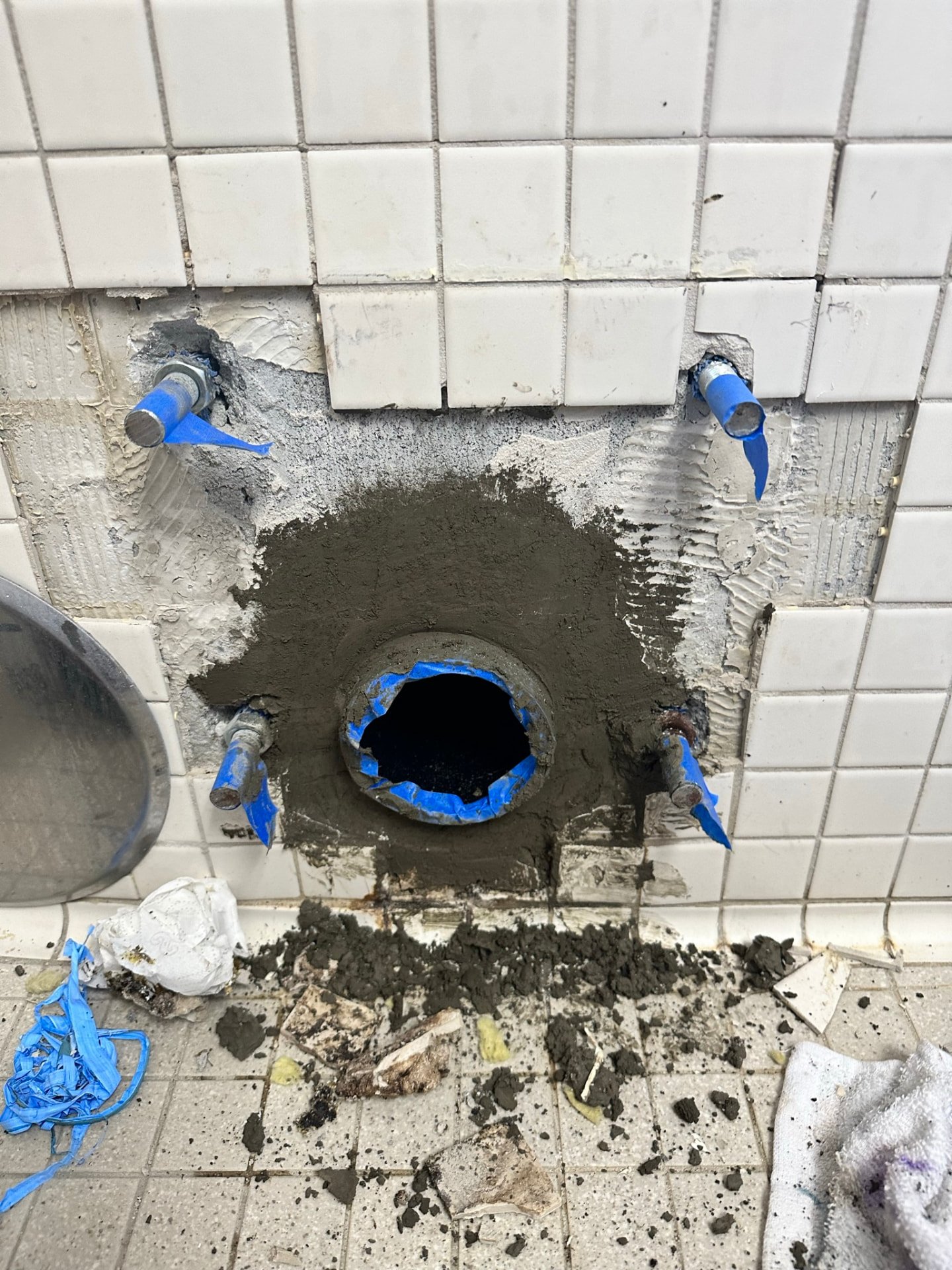 Repaired commercial toilet carrier opening patched and prepped in a tile wall