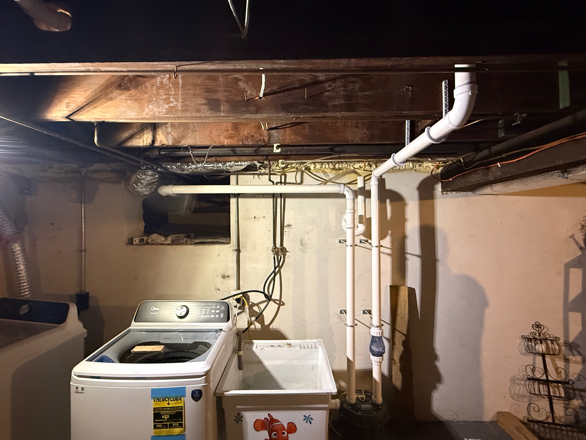 Sump pump and drainage piping installed beside laundry appliances in a Hamden basement