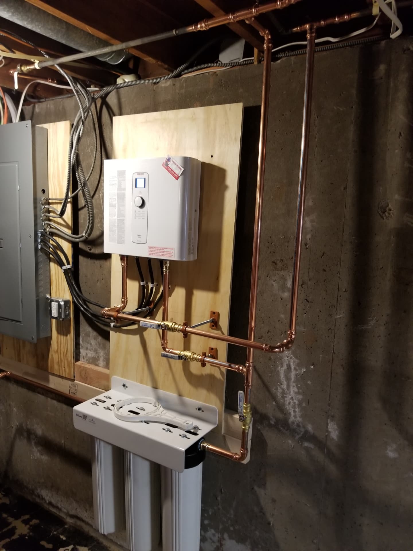 Electric tankless water heater installed with new copper piping and shutoff valves in a Connecticut basement