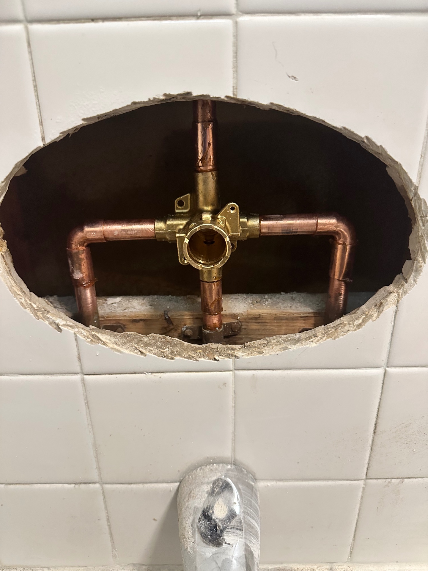 Exposed copper shower valve and piping inside a tiled Wallingford shower wall