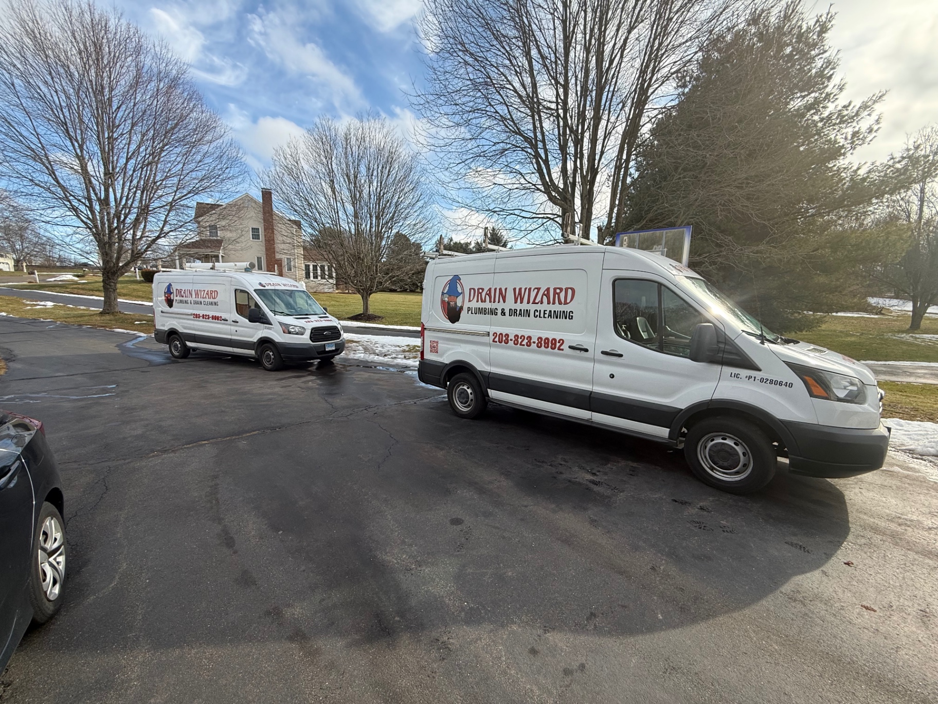 Two branded Drain Wizard service vans parked outside a Wallingford home