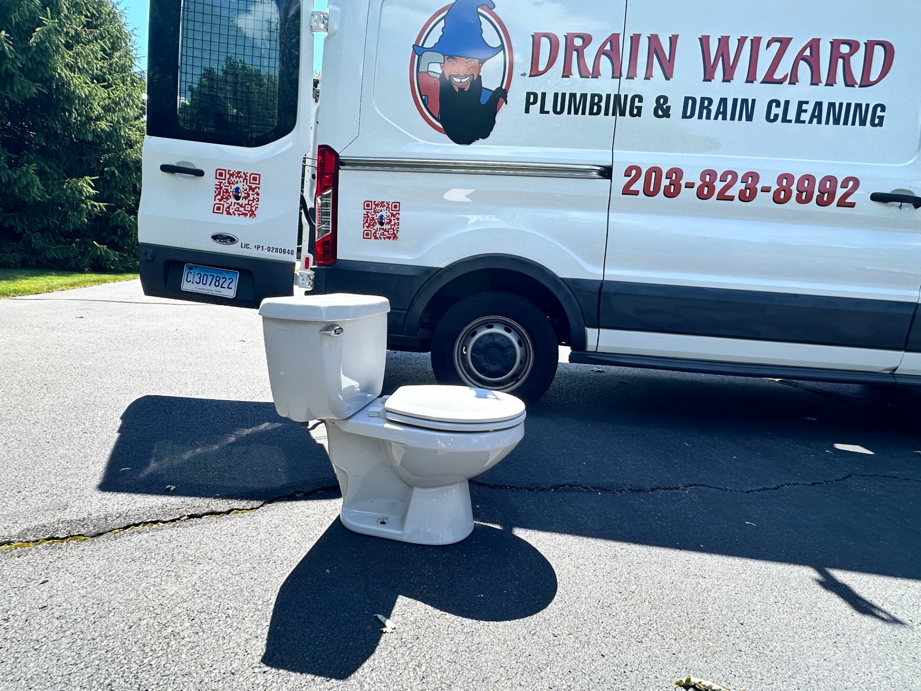 Branded Drain Wizard van beside a toilet staged outdoors for delivery in Wallingford